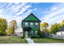 Charming two-story home with a striking green exterior, complemented by a bright yellow door and landscaped yard at 1221 Herbert St, Indianapolis, IN 46202