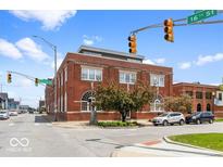 Street view of a three-story red brick building with a modern addition on top under a bright blue sky at 1529 Alabama N St # H, Indianapolis, IN 46202