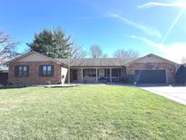 Traditional brick home with a covered front porch, mature trees, and a wide driveway, offering classic curb appeal at 1733 Beech Cir, Plainfield, IN 46168