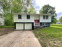 Split-level home featuring a red door and attached two-car garage with a concrete driveway at 2928 Sheffield Dr, Indianapolis, IN 46229