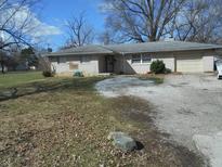 A single-story home with a light-brick facade and attached garage, set on a large lot with sparse landscaping at 3914 N Lesley Ave, Indianapolis, IN 46226