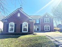 Inviting two-story brick home featuring arched windows, dark shutters, and a well-manicured front yard at 6191 E Ayrshire Cir, Camby, IN 46113