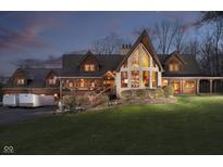 Dusk view of the charming home featuring stone accents, wood siding, and a well-manicured lawn at 222 Stony Ln, Noblesville, IN 46060