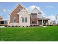 Charming two-story brick and stone home with a well-manicured lawn and inviting front porch at 3989 Birkdale Dr, Carmel, IN 46033