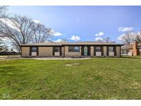 Charming brick home with a well-manicured lawn and vibrant green grass under a bright sky at 202 Rainbow Blvd, Indianapolis, IN 46234