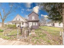 Two-story home featuring a chain-link fenced yard and a weathered wooden ramp leading to the entrance at 215 S Warman Ave, Indianapolis, IN 46222