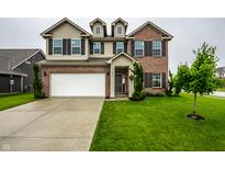 Charming two-story home featuring a well-manicured lawn, brick and tan siding, with an attached garage and cozy front porch at 647 Albermarle Dr, Pittsboro, IN 46167
