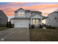 Charming two-story home featuring a two-car garage, covered porch with seating, and well-maintained landscaping at 6630 Overlander Ln, Whitestown, IN 46075