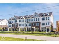 Attractive townhome complex with brick and siding, accented by green grass, trees, and a rustic wood fence at 14539 Hanford Ln, Carmel, IN 46032