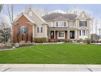 Beautiful two-story home with a well-manicured lawn, red brick facade, and inviting covered front porch at 14577 Faucet Ln, Fishers, IN 46040