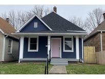 Charming blue house with white trim, gray steps and a pink front door at 1518 Lawton Ave, Indianapolis, IN 46203