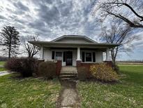 Charming home with a covered front porch and brick accents, surrounded by a green yard and mature trees at 3179 W 400 N, Fairland, IN 46126