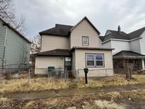 Exterior view of a tan two-story home with a chain link fence, and an overcast sky at 413 W 8Th St, Muncie, IN 47302