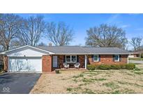Charming brick home featuring an attached garage and inviting front porch at 5240 Magnolia Dr, Columbus, IN 47203