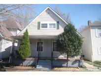 Charming house featuring a cozy front porch and meticulously landscaped yard with vibrant evergreens at 657 Birch Ave, Indianapolis, IN 46221