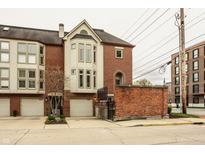 Brick townhome featuring attached garages and well-maintained landscaping with an inviting facade at 503 Lockerbie N Cir, Indianapolis, IN 46202