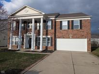 Traditional two-story brick home with white columns, two-car garage, and manicured front lawn at 5565 Noble Dr, Indianapolis, IN 46234