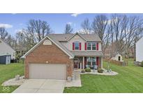 Charming two-story home featuring a brick facade, red shutters, manicured lawn, and attached two-car garage at 894 Woodgate Ln, Greenwood, IN 46143