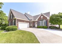 Charming brick home with a well-manicured lawn and a curved driveway leading to an attached two-car garage at 10844 Fairwoods Dr, Fishers, IN 46037