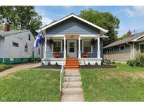 Charming blue home featuring a cozy front porch with seating and a well-maintained yard at 112 S Spencer Ave, Indianapolis, IN 46219