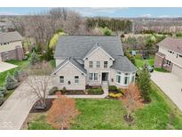 Stunning aerial view of a two-story home with gray roof, landscaped yard, and mature trees at 3892 Pelham Rd, Carmel, IN 46074