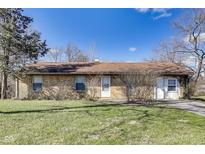 Cozy one-story home featuring a brick facade, mature trees, and a well-manicured lawn at 7906 E 21St St, Indianapolis, IN 46219