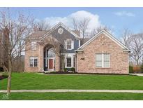 Beautiful brick home featuring a manicured lawn and elegant architectural details at 8228 Morel Dr, Indianapolis, IN 46256