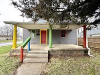Charming front porch with colorful posts on a home with gray siding and a red front door at 980 Edgemont Ave, Indianapolis, IN 46208