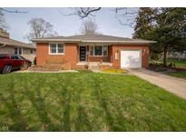 Charming brick home features a well-manicured lawn and attached garage, with inviting curb appeal at 1019 N Lesley Ave, Indianapolis, IN 46219