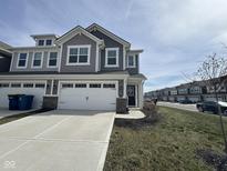 Charming gray townhome featuring a two-car garage, well-maintained lawn, and inviting curb appeal at 1239 Newton St, Avon, IN 46123