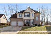 Two-story home featuring a well-manicured lawn, attached two car garage and neutral brick and tan siding at 5607 Regency Dr, Columbus, IN 47203