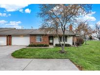 Charming single-story home featuring a brick facade, attached garage, and well-manicured lawn at 7607 Farm View E Cir, Indianapolis, IN 46256