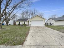 Charming single-story home featuring a well-manicured lawn, concrete driveway, and an attached two-car garage at 7228 Muirfield Pl, Indianapolis, IN 46237