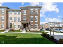 Beautiful new construction townhome featuring a brick facade, manicured lawn and a welcoming front porch at 13783 Tender Dr, Carmel, IN 46032