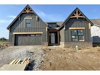 A modern farmhouse exterior with wood accents, dark gray siding, brick foundation, and a two-car garage at 1463 Crosstie Cir, Westfield, IN 46074