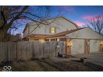 Exterior of the house with two garages and a fenced-in yard at dusk at 4814 Lynton Ct, Indianapolis, IN 46254