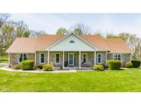 A charming single-story brick home features a well-manicured lawn and a cozy front porch with decorative chairs at 8654 N Baltimore Rd, Monrovia, IN 46157