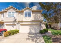 Inviting townhouse featuring a two-car garage, charming landscaping, and stone facade accents at 1045 Evening Shade Cir, Beech Grove, IN 46107
