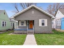 Charming bungalow featuring a textured gray exterior, orange front door, and a cozy front porch at 1310 N Chester Ave, Indianapolis, IN 46201