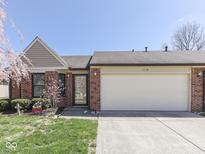 Charming brick home featuring an attached two-car garage, a well-manicured lawn, and a lovely flower bed at 1739 Wellesley Commons # 48A, Indianapolis, IN 46219