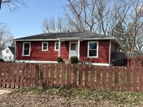 Charming red home featuring a well-maintained lawn and a traditional picket fence for added curb appeal at 2104 E 70Th St, Indianapolis, IN 46220