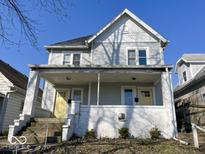 Two-story home featuring light gray wood siding and a welcoming covered front porch with white brick supports at 2148 Singleton St, Indianapolis, IN 46203