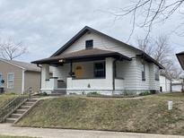 Charming bungalow showcasing a quaint porch, complemented by fresh white paint and a bright yellow front door at 2528 E 17Th St, Indianapolis, IN 46218