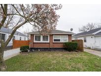 Cozy brick home featuring a well-maintained lawn and a mature tree with blossoming flowers in a peaceful residential neighborhood at 4711 East 21St St, Indianapolis, IN 46218