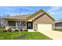 Charming brick home featuring a covered porch, well-manicured lawn, and attached two car garage at 5362 E Commons N Dr, Mooresville, IN 46158