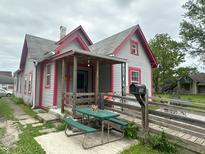 Charming home with gray siding, red trim, covered porch, wooden ramp, and picnic table at 554 N Tacoma Ave, Indianapolis, IN 46201