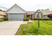 Charming brick home with a well-maintained lawn and attached two-car garage, complemented by a classic-style lamp post at 8737 Champions Dr, Indianapolis, IN 46256