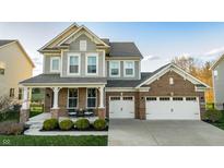 Charming two-story home with a brick and gray facade, a covered front porch, and a two-car garage at 15958 Oakhurst Ln, Fishers, IN 46040