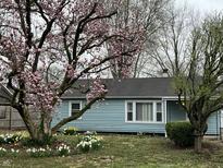 Charming blue house featuring a blossoming magnolia tree and a well-manicured front yard at 7131 E 14Th St, Indianapolis, IN 46219