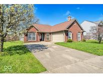 Charming brick home features manicured lawn, large windows, and a spacious two-car garage at 7854 Crooked Meadows Dr, Indianapolis, IN 46268